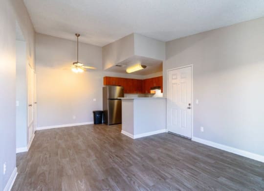 an empty living room and kitchen with a wood floor