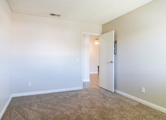 an empty living room with a door open to a hallway