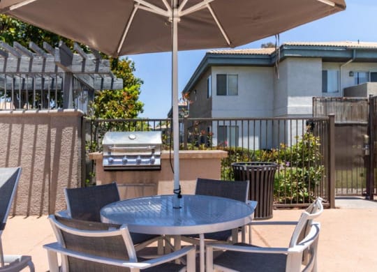 a patio with a table and chairs and a grill