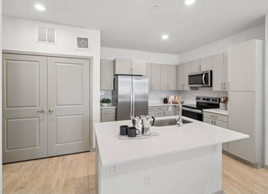 A modern kitchen with a white countertop and stainless steel appliances.