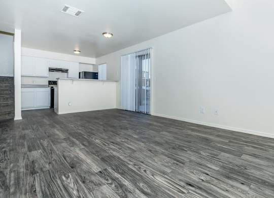 A spacious room with wooden flooring and white walls.