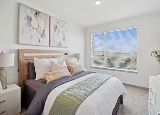 A bedroom with a large bed and two wall art pieces.
