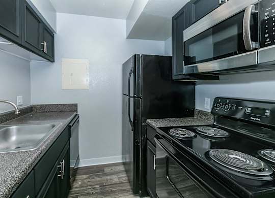 A black refrigerator and microwave in a kitchen.