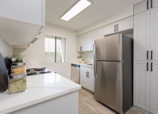 a white kitchen with a stainless steel refrigerator