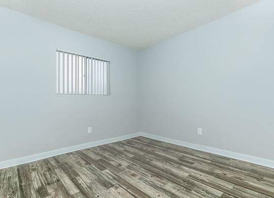A room with a window and wooden flooring.