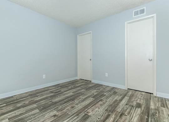 A room with a wooden floor and two doors.