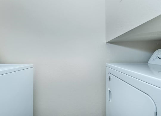 Two white washing machines in a laundry room.