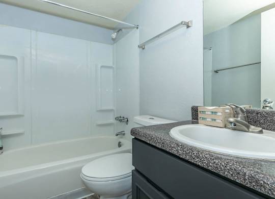 A white toilet sits next to a bathtub in a bathroom.