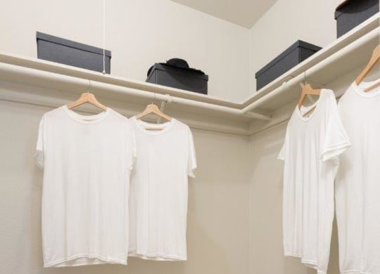 four white shirts hanging on a rack in a room