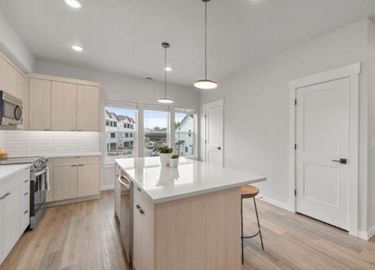 A modern kitchen with wooden floors and white walls.