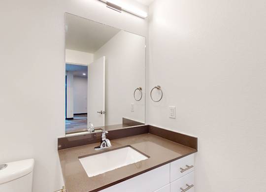 A bathroom with a sink, toilet, and mirror.