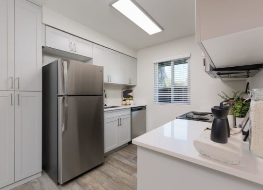 a kitchen with white cabinets and a stainless steel refrigerator