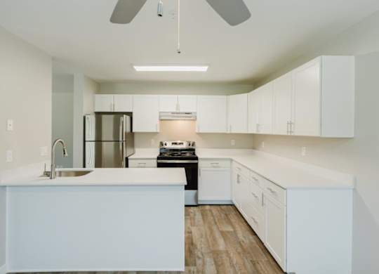 A modern kitchen with white cabinets and a wooden floor.