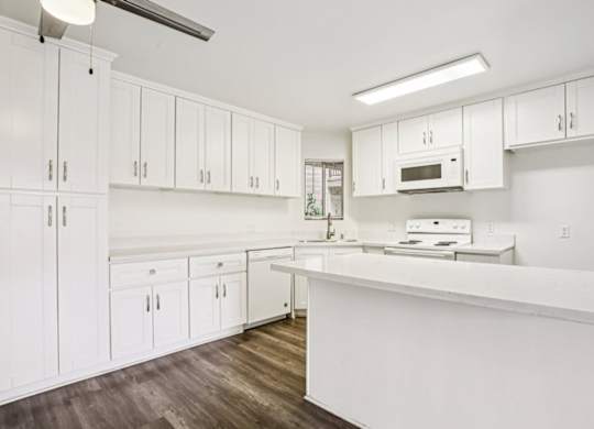 A kitchen with white cabinets and a white counter.
