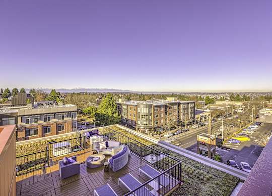 A rooftop patio with a table and chairs overlooks a cityscape.