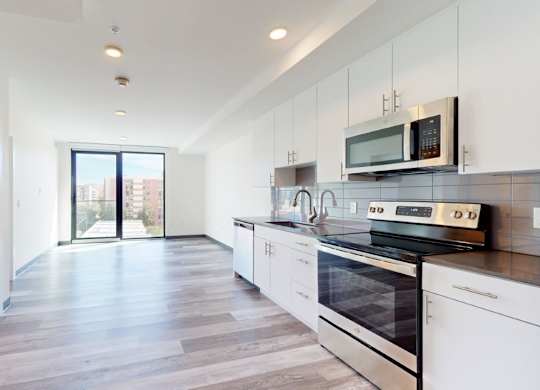 A modern kitchen with white cabinets and a black stove top oven.