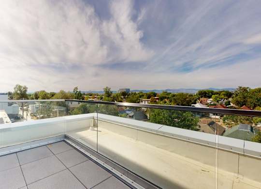 A balcony with glass railings overlooks a residential area.