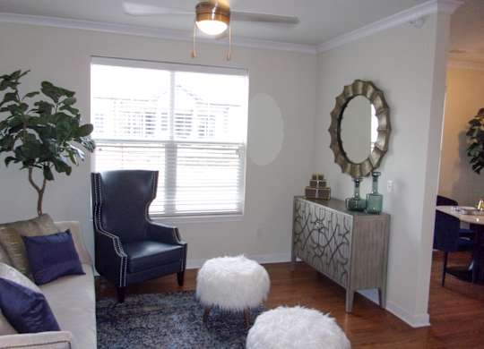 A living room with a blue chair and a white ottoman.