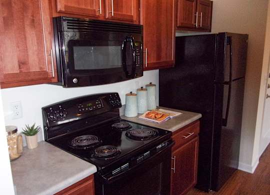 A black stove top oven with a black microwave above it.