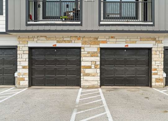 A house with two black garage doors and a stone pillar in the middle.