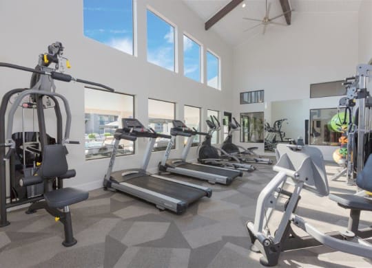 a gym with cardio equipment and windows in a building