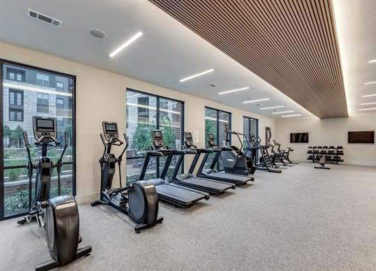 a gym with cardio equipment and windows in a building
