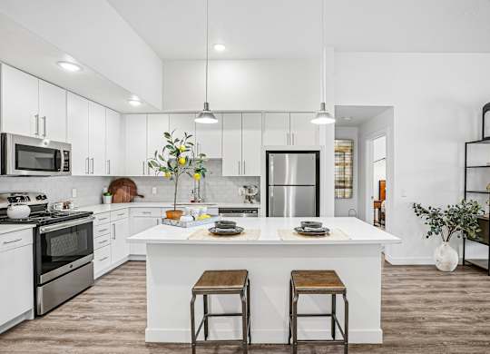 A modern kitchen with a white island and stools.