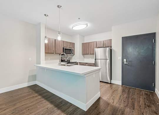 A kitchen with a refrigerator, microwave, and oven.