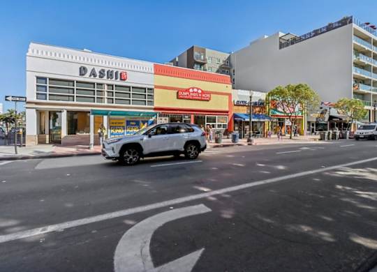 A white car is parked on the street in front of a Dashie store.
