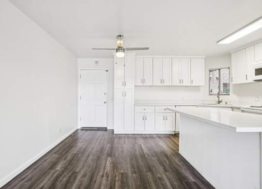A kitchen with white cabinets and a wooden floor.