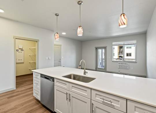 A kitchen with a white counter top and a dishwasher.