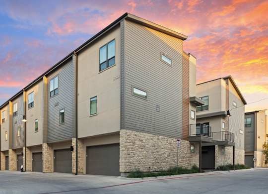 A modern apartment building with a sunset sky in the background.
