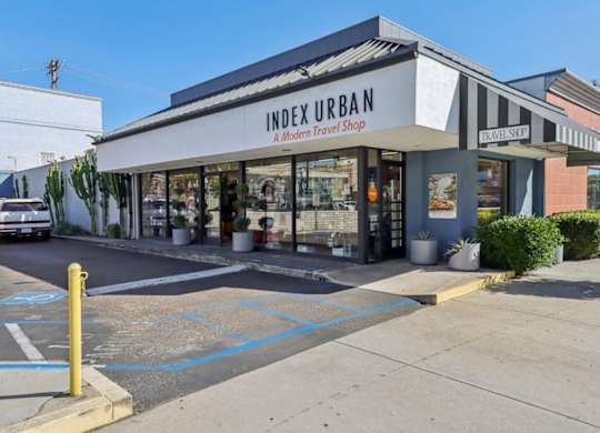 A modern travel shop named Index Urban is located in a parking lot.