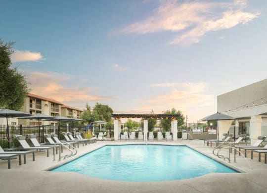 a swimming pool at a hotel with chairs and umbrellas