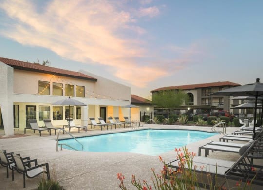 a swimming pool at a resort with chairs and umbrellas