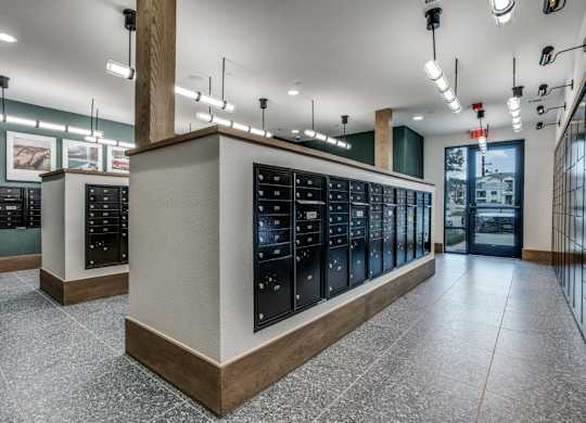 A row of black vending machines are lined up in a room with a tiled floor.
