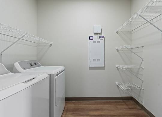 A laundry room with a washer and dryer and a wall-mounted dispenser.