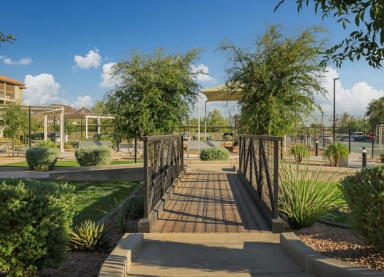 a bridge in a park with trees and a fence