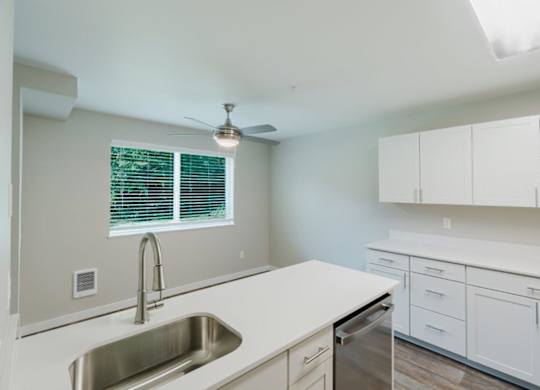 A kitchen with white cabinets and a stainless steel sink.