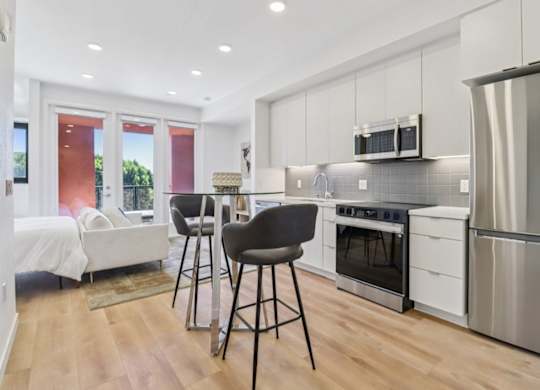 A modern kitchen with white cabinets and a wooden floor.
