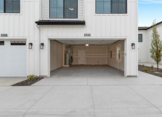 A white garage door is open to reveal a spacious garage.