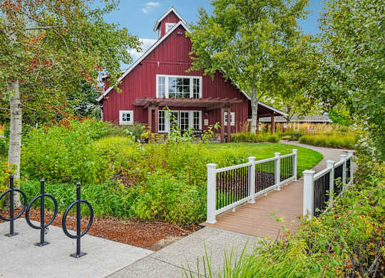 A red barn with a white fence and a walkway in front.