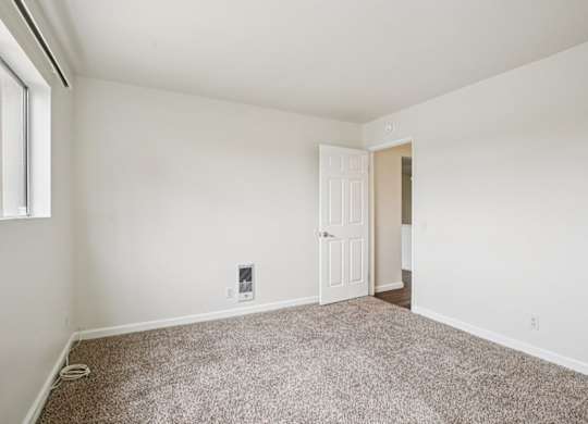 A room with a carpeted floor and a white door.