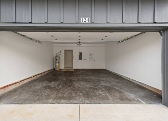 A large, empty garage with a concrete floor and a door at the end.