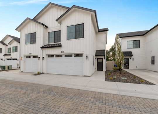 A row of white houses with black roofs and garage doors.