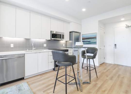 A kitchen with white cabinets and a grey counter top.