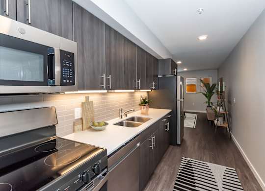 A modern kitchen with dark wood cabinets and stainless steel appliances.