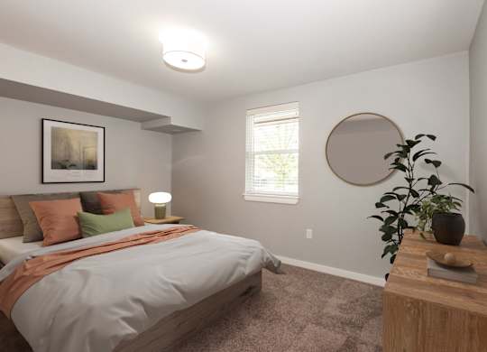 A bedroom with a bed, a lamp, a plant, and a picture on the wall.