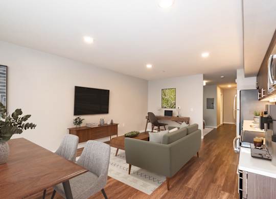 A modern living room with a grey couch, a wooden dining table, and a television.