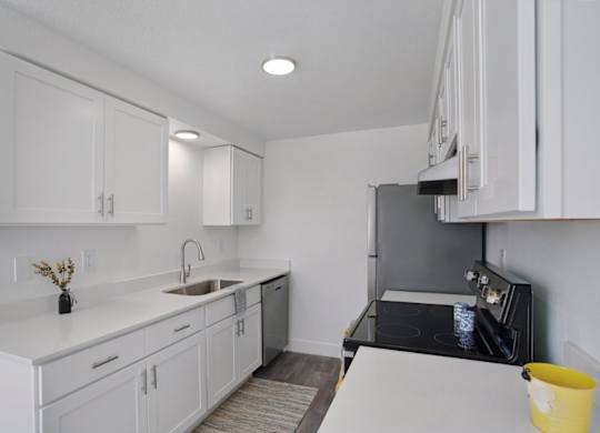 A kitchen with white cabinets and a black stove top oven.